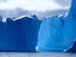 A panoramic photograph of massive, deep blue icebergs floating on the ocean under a dramatic and cloudy sky. MapHub's new Multi-Select tool.