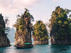 A tour boat navigates on calm water between several large, tree-covered limestone rock formations, representing the organization of map items into groups. navigation as clear as a path between islands.