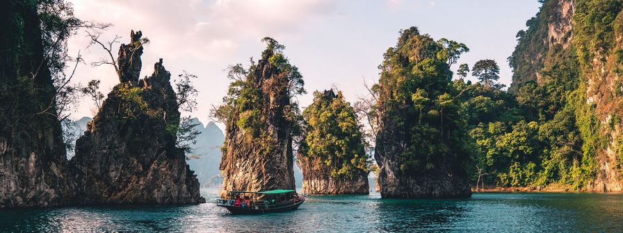 A tour boat navigates on calm water between several large, tree-covered limestone rock formations, representing the organization of map items into groups. navigation as clear as a path between islands.