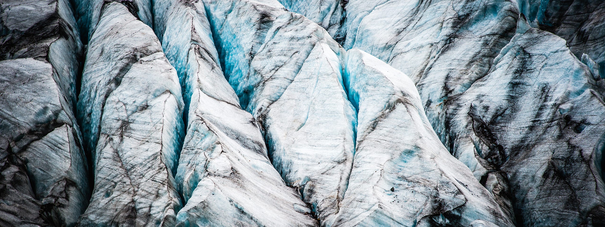 A detailed, close-up photograph of a glacier's surface, showing sharp white peaks, vibrant blue ice in deep crevasses, and layers of dark sediment. clear and transparent commitment to GDPR compliance.