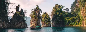 A tour boat navigates on calm water between several large, tree-covered limestone rock formations, representing the organization of map items into groups. navigation as clear as a path between islands.