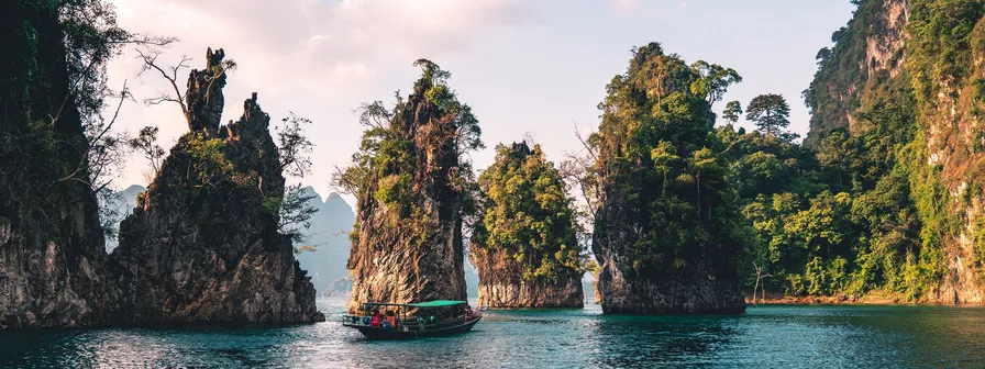 A tour boat navigates on calm water between several large, tree-covered limestone rock formations, representing the organization of map items into groups. navigation as clear as a path between islands.