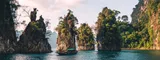 A tour boat navigates on calm water between several large, tree-covered limestone rock formations, representing the organization of map items into groups. navigation as clear as a path between islands.